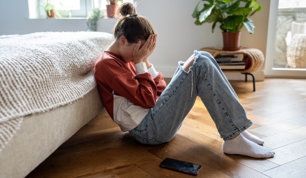 teen sitting on floor depressed with phone. 