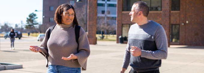 student walking outside while talking with tim matthews. 