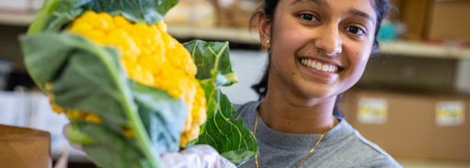 UB student Srikrithi Krishnan, a master’s student in the School of Public Health and Health Professions, bags fresh, in-season produce for the Food Box initiative in July 2023. The group is partnering with FreshFix, a local food distributor, to bring food to people experiencing food insecurity. Photographer: Douglas Levere. 