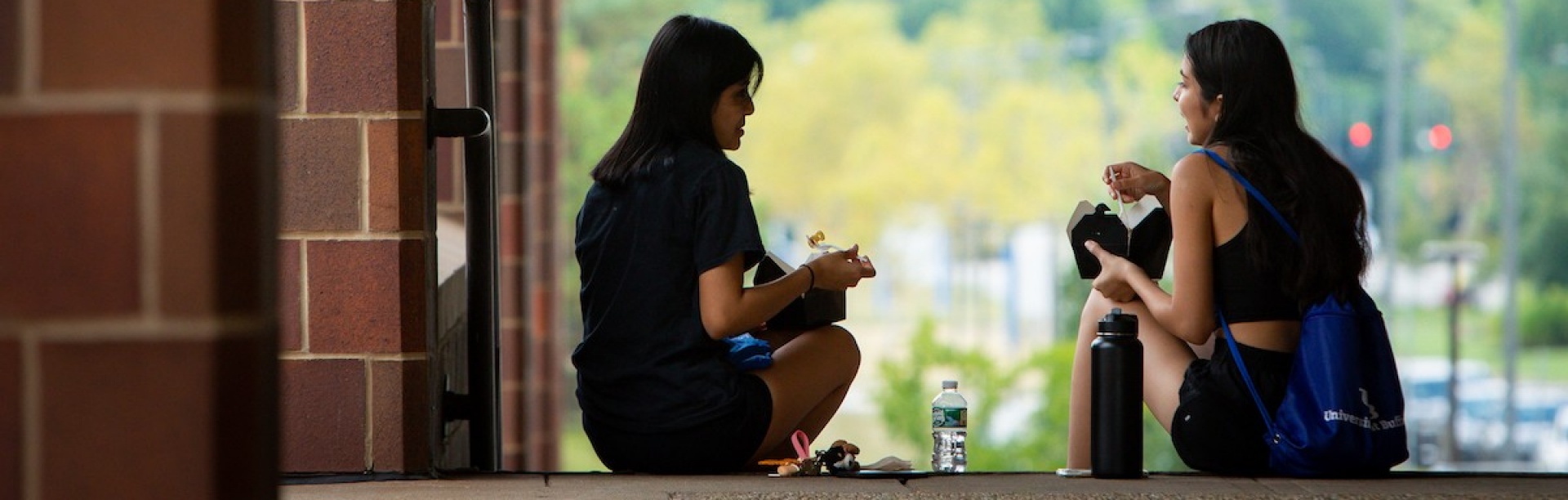 two people having lunch and a conversation while sitting on stairs. 
