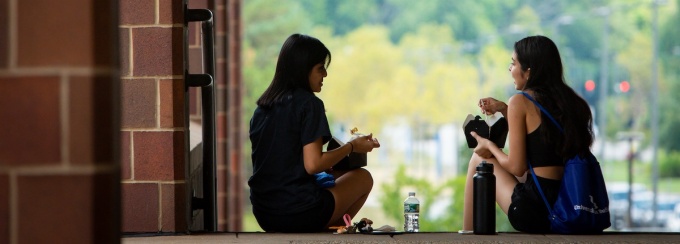 two people having lunch and a conversation while sitting on stairs. 