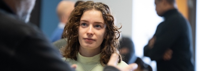 student at an event having a conversation with someone in the foreground. 
