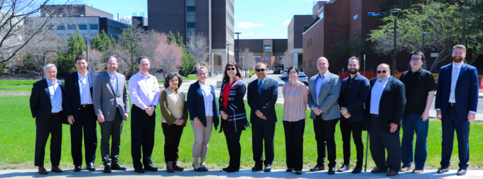 Every member of the IBE advisory board along with each IBE faculty member stand in front of some of the engineering buildings on a sunny day. 