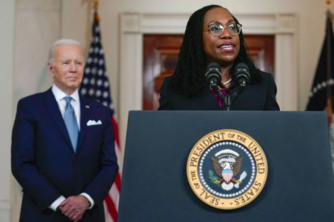 Picture of Judge Ketanji Brown Jackson at a podium being nominated as the the 116th Associate Justice of the United States Supreme Court, with President Joe Biden smiling in the background. 
