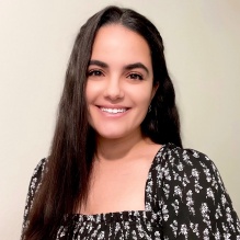 Aya Shhub smiling with dark shirt and white pattern in clear background. 