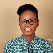 Adedoyin Inaolaji smiling in a headshot with a shirt with patterns with indoor clear background. 