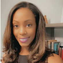 Brittany Jones smiling with dark shirt in indoor background with books in the back. 