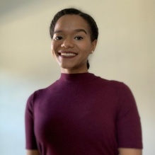 Lynnora Grant smiling infront of a white backdrop. 