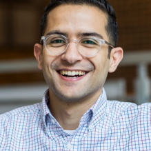 Bruno Saconi smiling in front solid background. 
