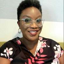 Oluwanfunke Brinda smiling infront of a white backdrop. 