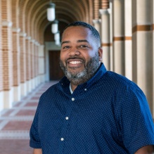 Quintin Gorman, Jr. smiling in a blue shirt on an outside building background. 