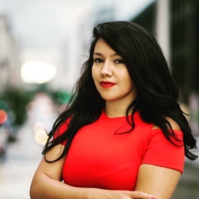 Amy Fallas smiling in a red shirt on an outside background. 