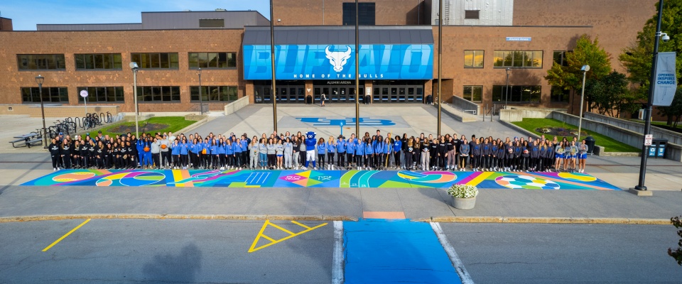 women athletes posing on a mural celebrating 50 years of title ix at UB. 