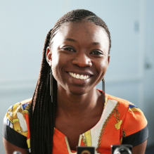 Oluwanfunke Brinda smiling infront of a white backdrop. 