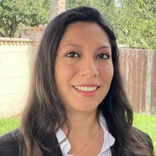 LuBeth Pérez smiling in a black blazer and white shirt on an outside background. 