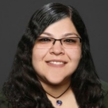 Veronika Espinoza smiling with dark shirt in clear gray background. 