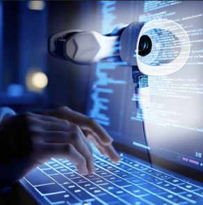 A close-up, blue-toned image shows a person typing on a laptop keyboard while a AudioSight (assistive health technology device) hovers above or beside the screen. The screen displays lines of code or data in a glowing interface, suggesting software development or data analysis. 