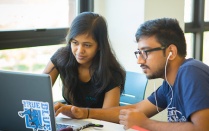 Two students looking at a laptop together. 