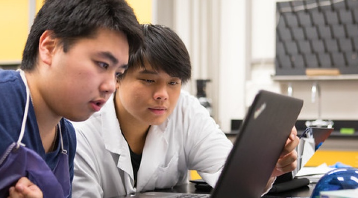Two students working on a laptop in a lab. 