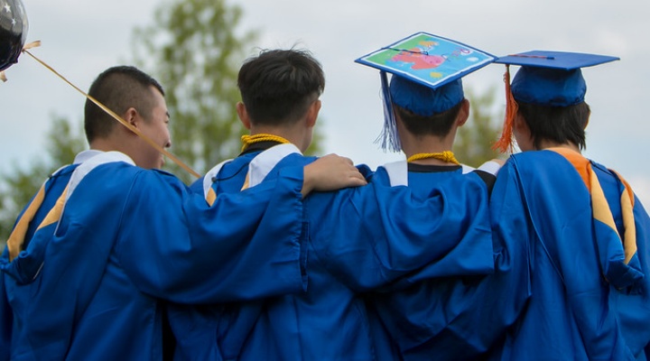 Four students in graduation caps and gowns. 