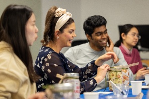 Students and a staff members sittting toehter working on a craft.