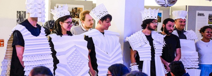 People wearing sculpted paper costumes. 