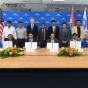 UB administrators and others posing with signed papers. 