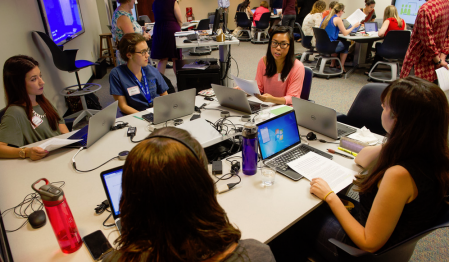 Student team gathered around a table in mid-discussion. 