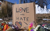 a cardboard sign that read 'love over hate' at a memorial space. 