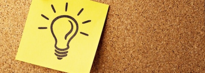 A hand drawn image of a lightbulb on yellow post-it paper, pinned to a cork board. 