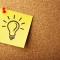 A hand-drawn image of a lightbulb on yellow post-it paper, pinned to a cork board. 