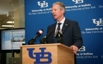 Photo of Larry Wrabetz, Founding Director, standing a podium with the UB decal on the front of the podium, as well as the UB logo in the background. 