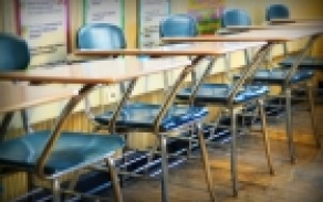 empty desks lining the back of a classroom. 