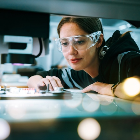 Robotic engineer woman developing robot arm in semiconductor factory. Focused on high-precision automation in microchip Research and Develop environment. 