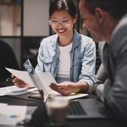 Royalty-free stock photo ID: 1828969643 Smiling young Asian businesswoman going over paperwork with a male colleague during a meeting around a boardroom table. 