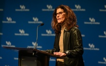 Beth Del Genio, PhD, speaks at a podium. 