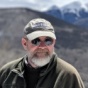 picture of Gregory Valentine. Pictured with hat on and sunglasses with mountains in the background. 