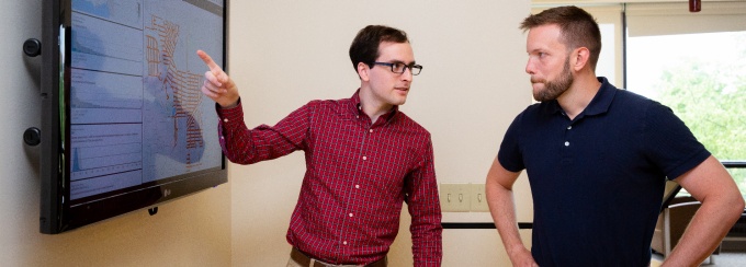 Man on left explaining a concept to a man on the right. 