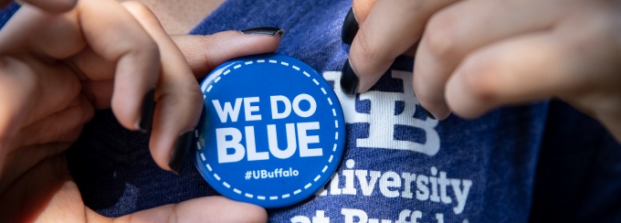 University at Buffalo shirt and pin that says "we do blue". 