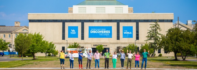 A group of people standing and waving in front of Abbott Library. 