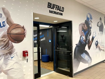 Entrance to UB Recreation Member Services, surrounded by large wall graphics of Buffalo Bulls student-athletes competing in basketball, football, and swimming. 
