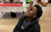 student sitting in a chair leaning his head back with an oreo cookie in the middle of his face. 