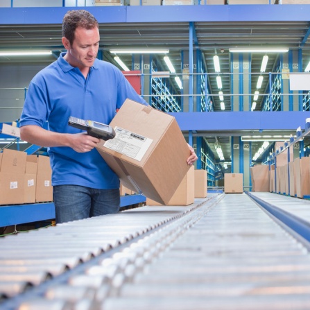 Employee scanning a package on a conveyor belt. 