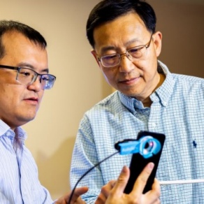 Wenyao Xu, left, and Wei Sun, right, examine the smartphone-controlled hearing test. 
