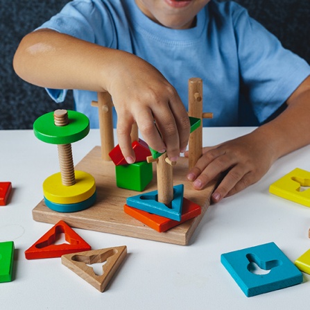 Child plays with wooden toy sorter. Early childhood development. 