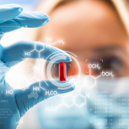 Scientist holding a pill with digital formula rendering around it. 