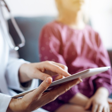 Physician noting patient test results in touchpad. 
