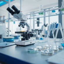 Microscope and lab supplies on countertop like pipettes, petri dish, flasks, etc. 