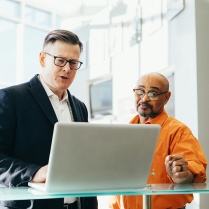 Two men looking at a computer. 