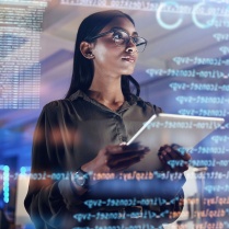 Woman working on a computer, looking at code on a screen. 